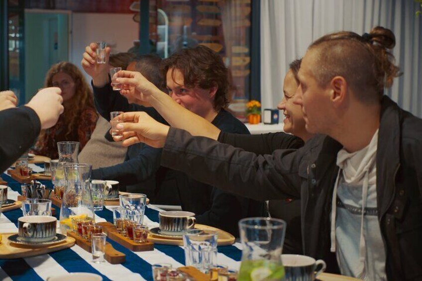 Un grupo de personas brindando con bebidas en una mesa con varios vasos y platos. 4