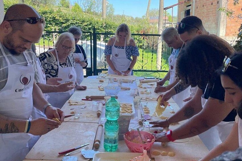 A group of people wearing aprons, engaged in food preparation activities around a table. 3