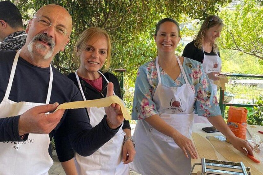 People wearing aprons, working with dough on a table outdoors. 2