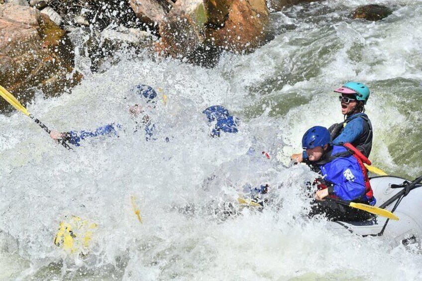 Two people in a white raft navigating a river with rapids. 4