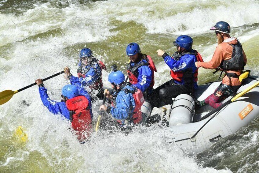A group of people in a raft navigating through rough waters. 1
