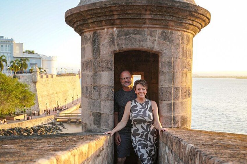 A couple standing in front of a stone structure by the water. 4