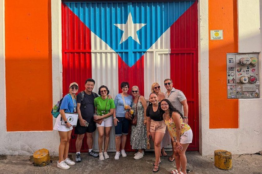 A group of people posing in front of a building with a large flag. 3