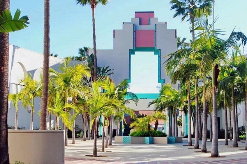 A modern building with a geometric facade, surrounded by palm trees and a paved walkway. 4