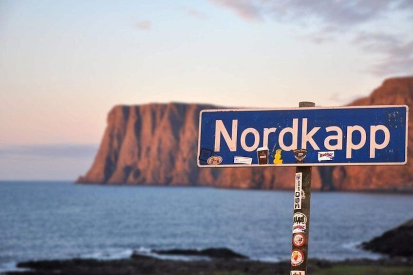 Un panneau indiquant le mot « Nordkapp » sur fond de paysage côtier avec des falaises. 1