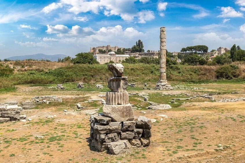 Ancient ruins with stone columns and a large stone structure in a grassy field. 5