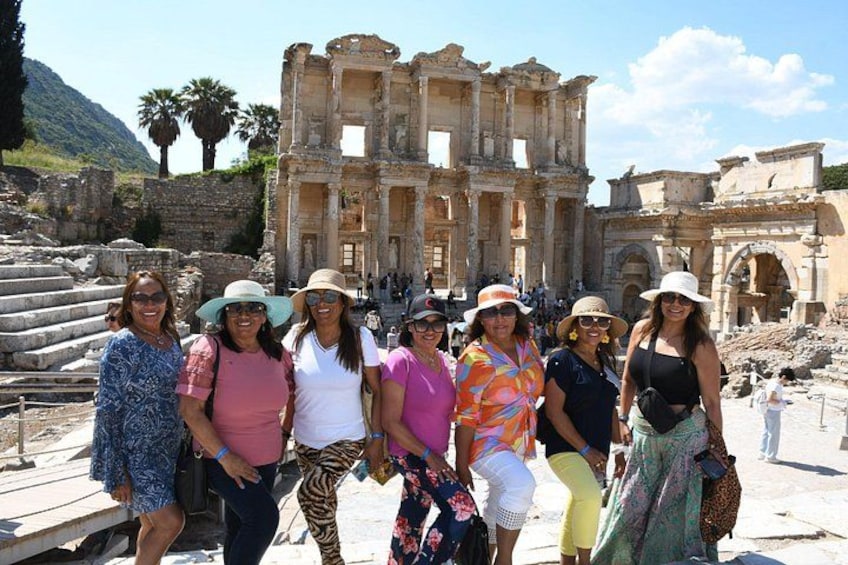 A group of people standing in front of ancient ruins with a large stone structure in the background. 1