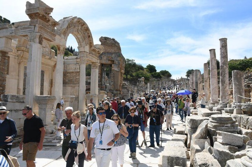Ancient ruins with columns and arches, tourists walking around, and a clear sky. 3