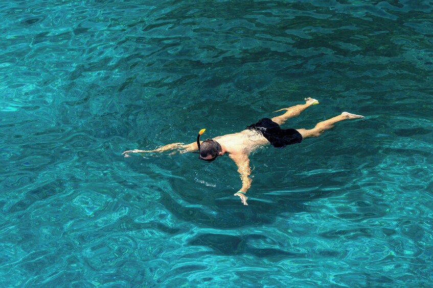 A person swimming in clear blue water. 3
