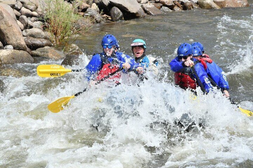 Three people kayaking on a river with rapids. 3