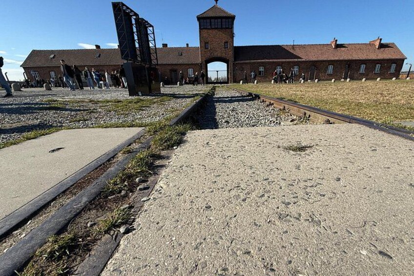 Un edificio histórico con una torre, una vía de tren y una zona de grava. 3
