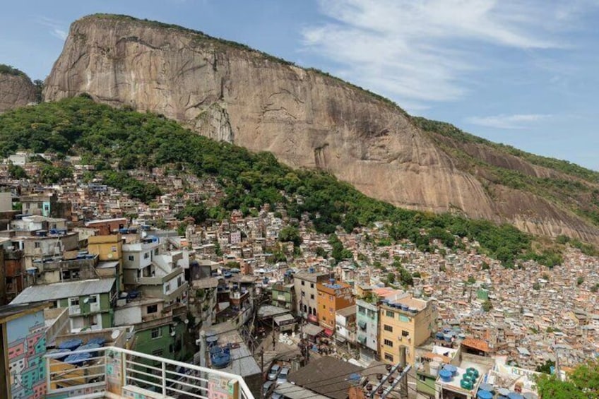 A densely populated hillside town with colorful buildings and a large cliff in the background. 2