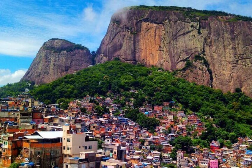 A densely packed urban area with colorful buildings, a large mountain in the background, and lush green vegetation. 5