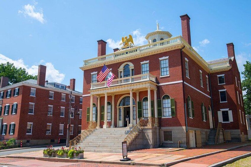 A red brick building with a white balcony, American flags, and a gold statue. 2