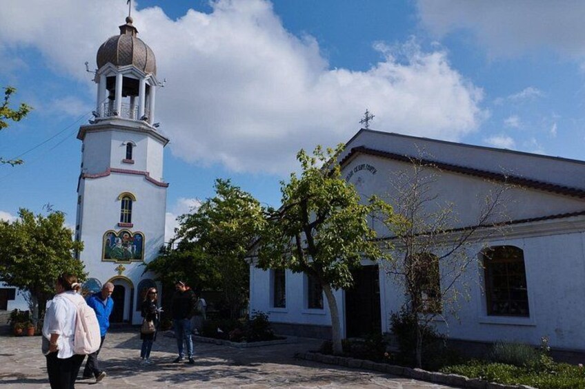 A church with a bell tower, a white building with a red roof, and a clear blue sky. 5