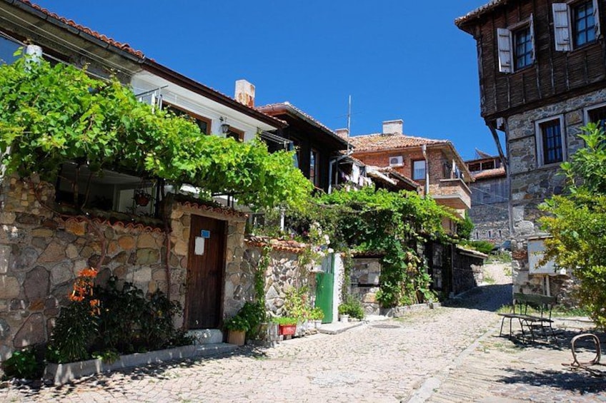 A cobblestone street with stone buildings, a wooden door, and a green mailbox. 3