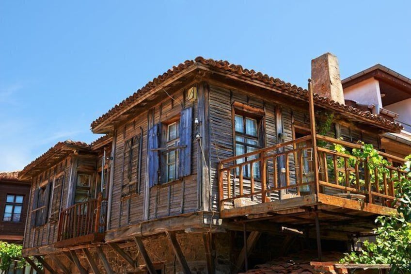 A rustic wooden house with a balcony, a chimney, and a tiled roof. 2