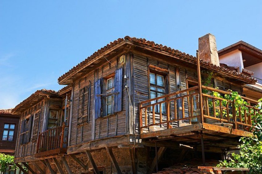 A rustic wooden house with a balcony, a tiled roof, and a chimney. 4