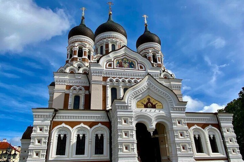 A white and brown church with three domes and a golden cross. 4