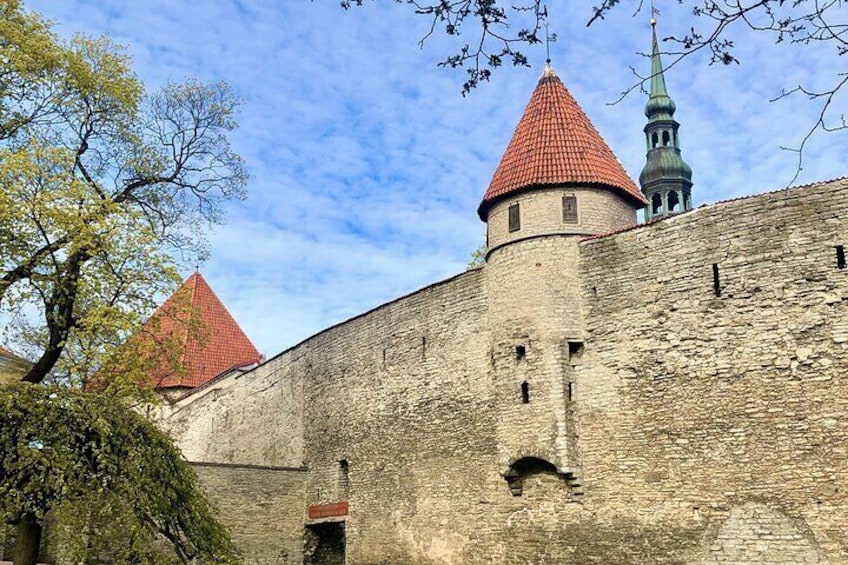 A historic stone wall with a tower and a church spire. 3