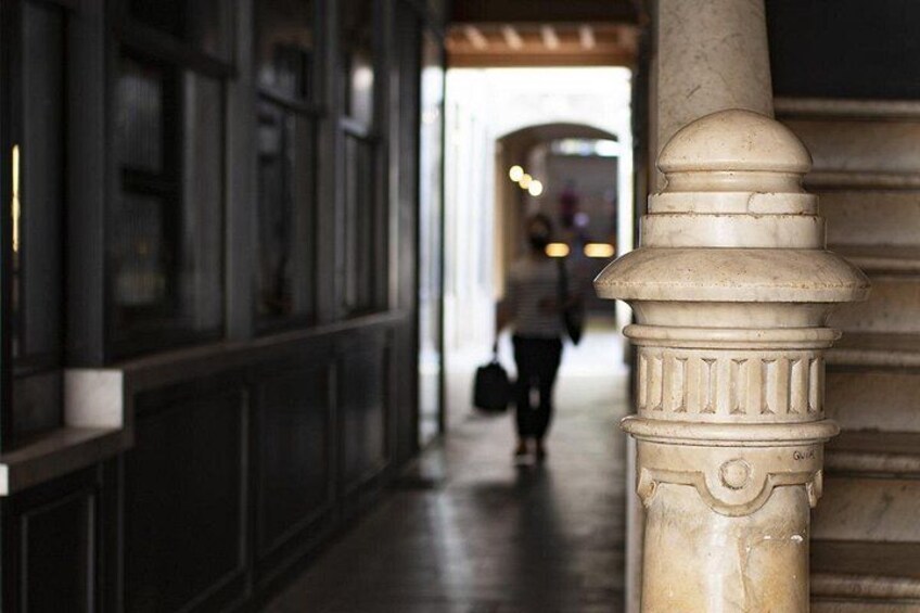 A corridor with a column, a person walking, and a door in the background. 3