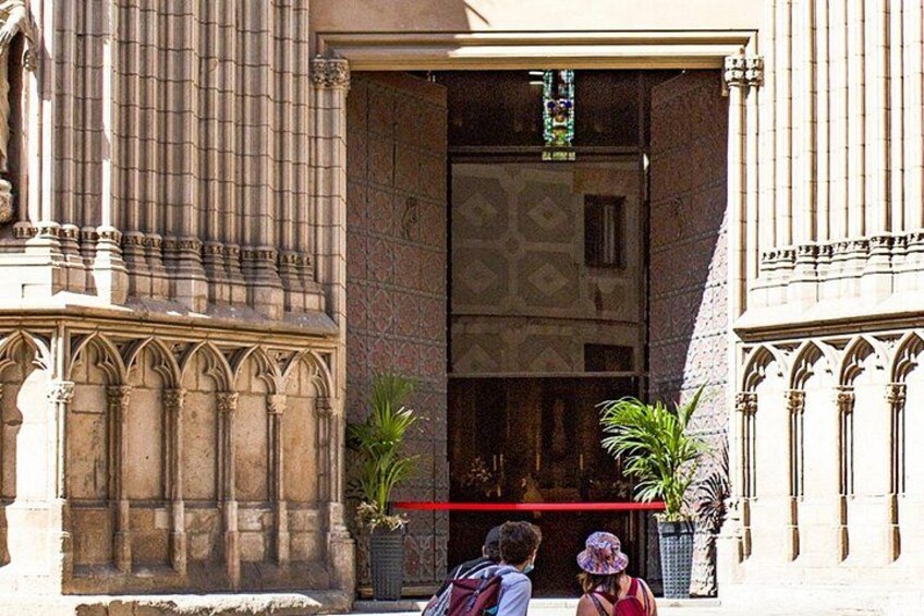 A building entrance with a large stained glass window, stone columns, and potted plants. 5