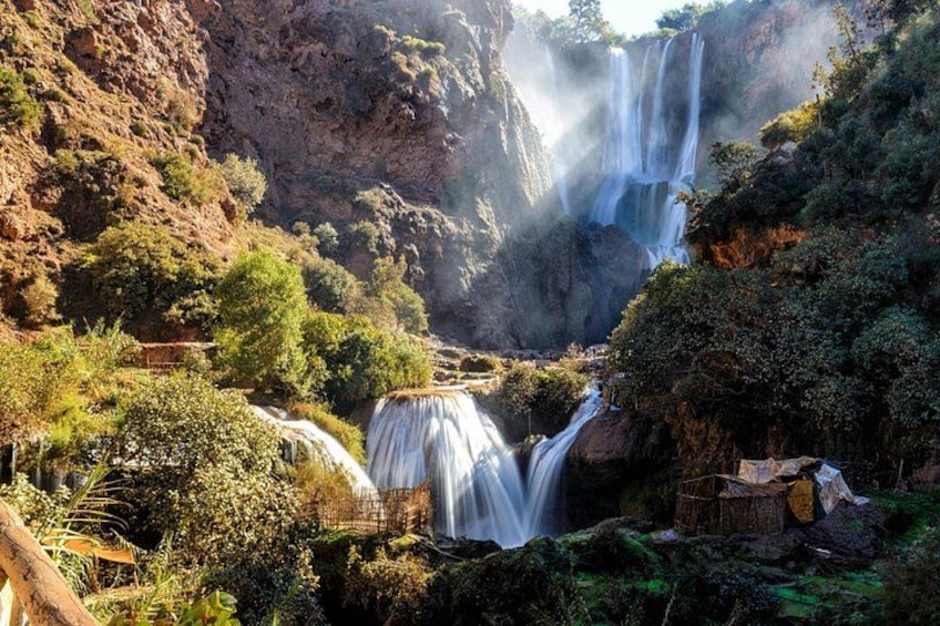 Ein Wasserfall stürzt über eine felsige Klippe, umgeben von üppigem Grün. 2