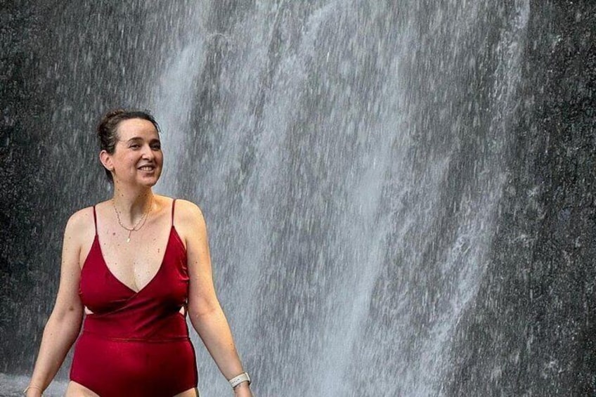 A person in a red dress standing in front of a waterfall. 3