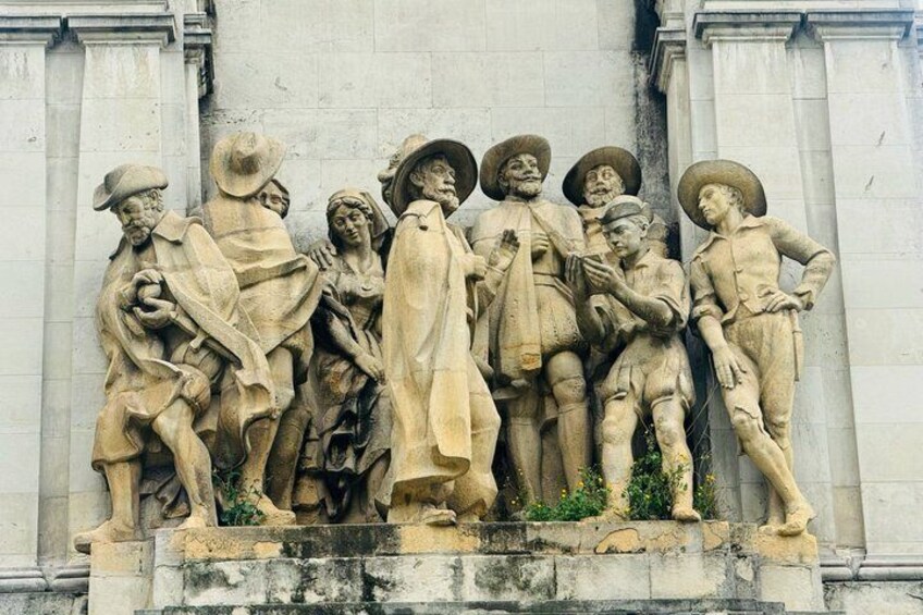 A stone relief sculpture of a group of people on a building facade. 3