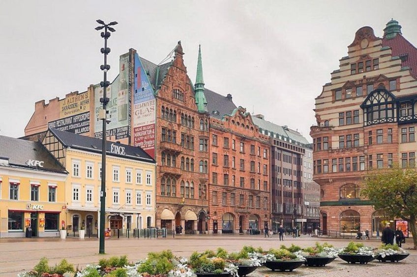 A historic European city square with traditional architecture, a KFC, and a tram line. 1