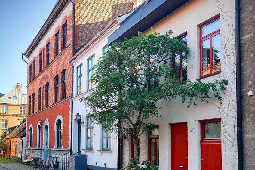 A row of colorful buildings with red and white facades, a tree in the foreground, and a bicycle parked outside. 4