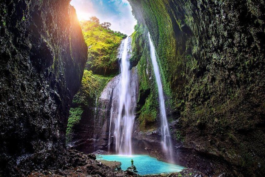 A waterfall cascading into a turquoise pool surrounded by rocky cliffs. 1