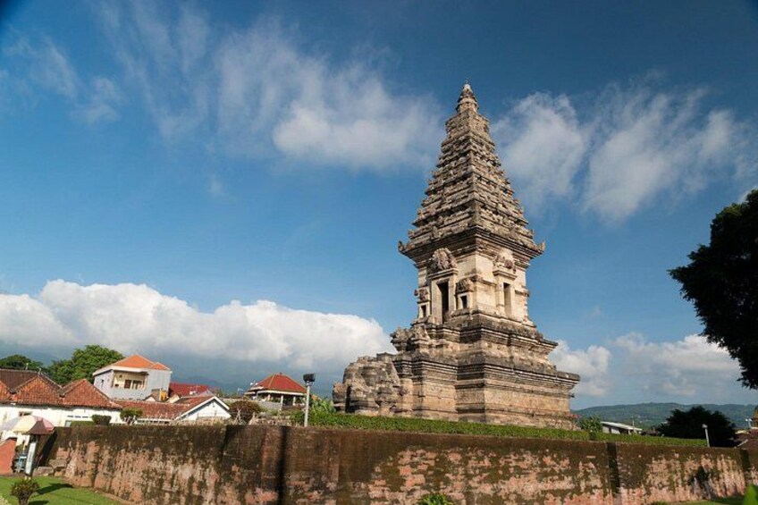 A large stone temple with a tiered tower, surrounded by a low wall and a clear sky. 4