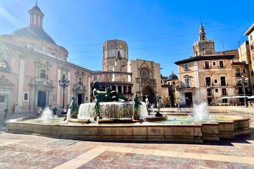 A historic square with a central fountain, surrounded by classical architecture. 2