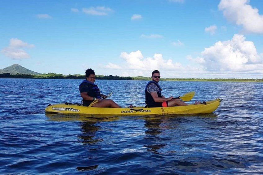 Two people kayaking on a calm body of water with a mountain in the background. 3