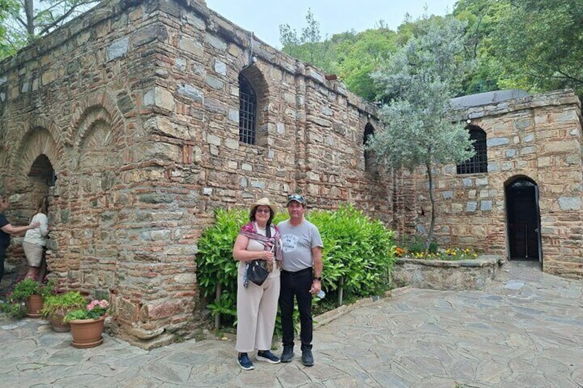 A stone building with arches and a door, surrounded by potted plants and a pathway. 5