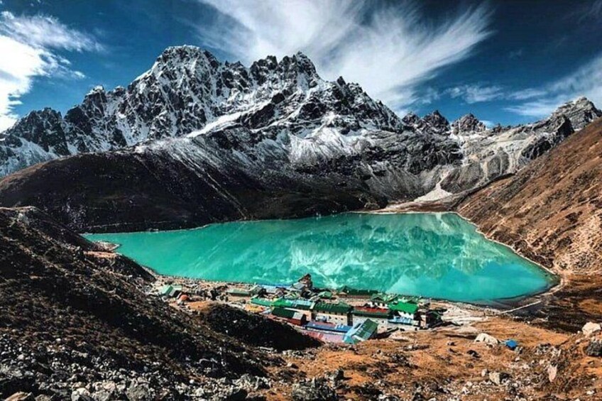 A turquoise lake surrounded by mountains, with a small settlement in the foreground. 1