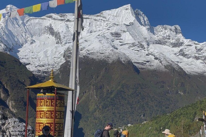 A snow-capped mountain, a prayer flag, and a small shrine. 3