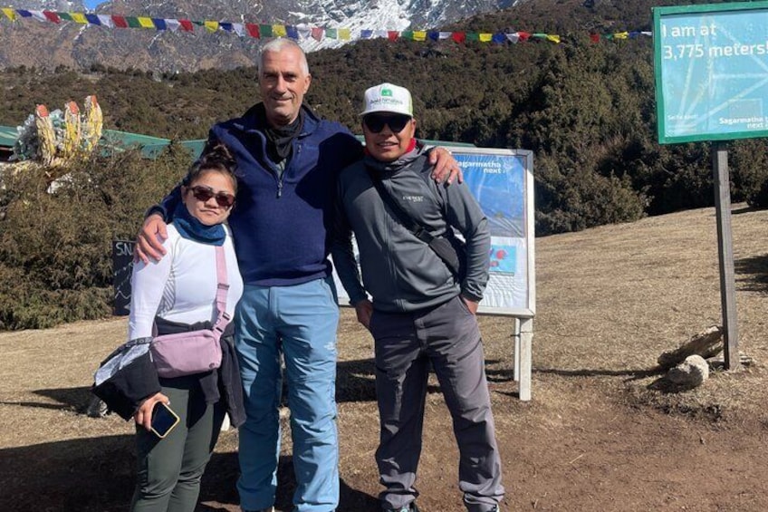 Three people standing in front of a sign indicating elevation. 2