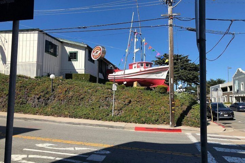 Una calle con un barco rojo y blanco en tierra, un edificio con un letrero y una borda roja. 5