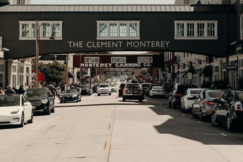 A street with parked cars and a building with a sign that reads 'The Clement Monterey.' 2