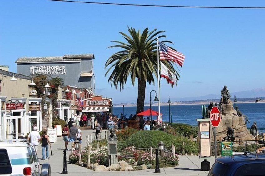 Un pueblo costero con tiendas, una estatua y una palmera. 4