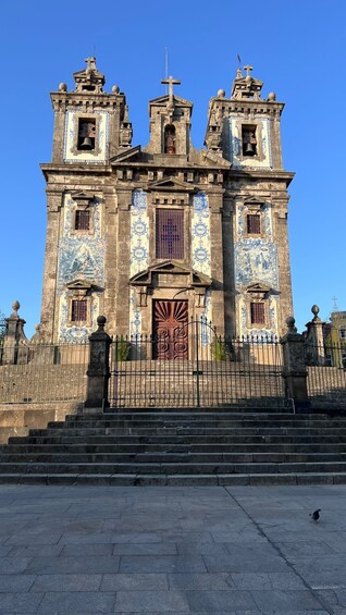A historic church with a bell tower, ornate facade, and a large wooden door. 5