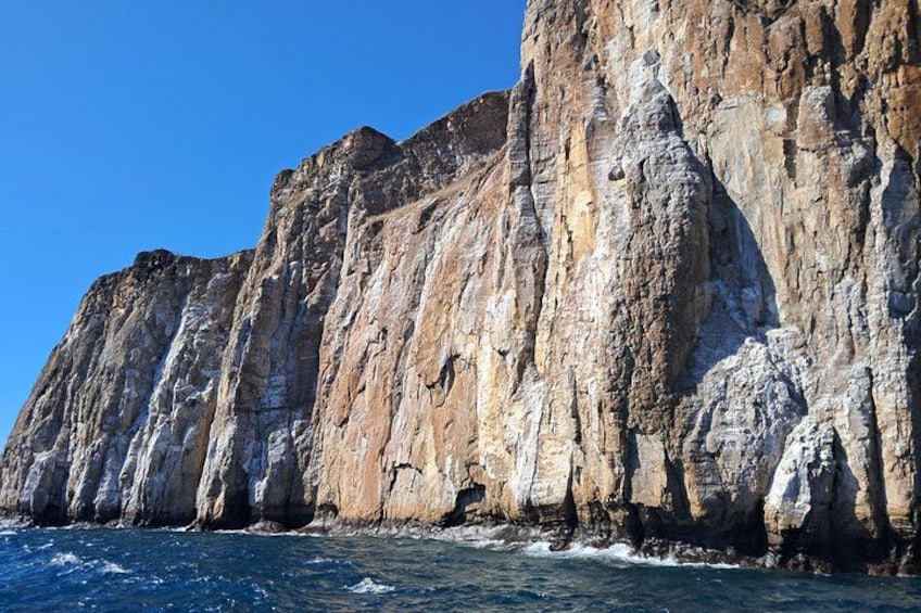 A coastal cliff with rugged terrain and a clear blue sky. 3