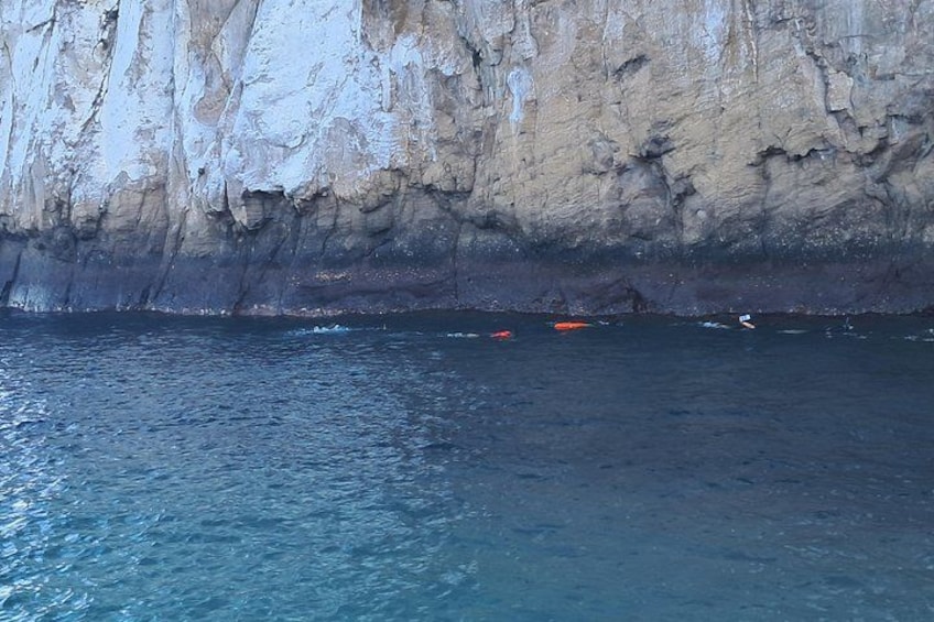 A rocky cliff by the sea with clear water. 2