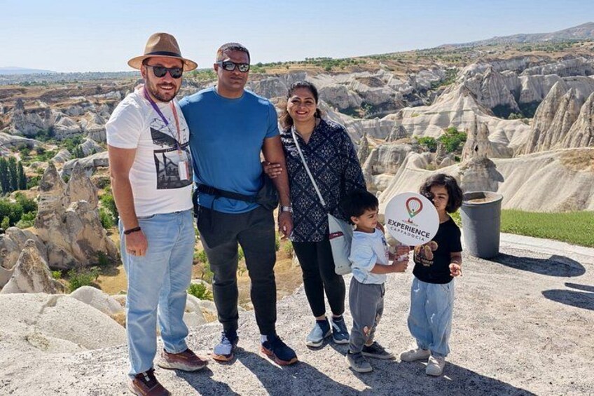 A family of four at a rocky outcrop with a panoramic view of a rugged landscape. 1