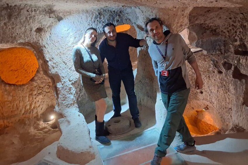 Three people inside a cave with rough walls and a circular opening. 3
