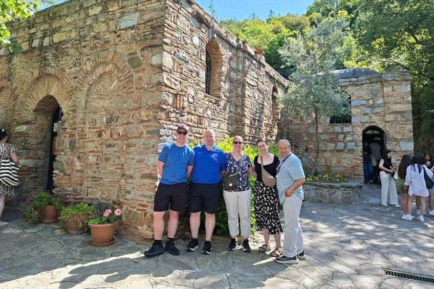 A group of people standing in front of a stone building with arches. 2