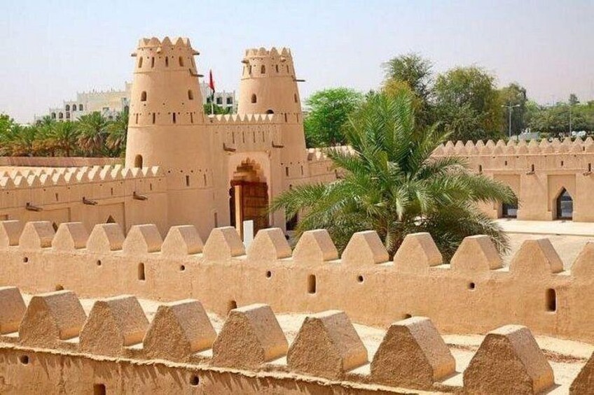 A fortress with crenellated walls and two towers, palm trees, and a clear sky. 2