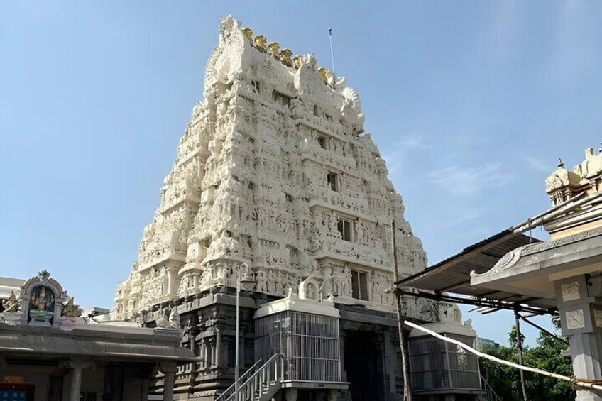 A white temple with intricate carvings and a large, ornate entrance. 5